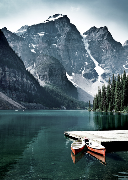  – Photographie d’un lac avec une petite jetée et deux canots devant des montagnes
