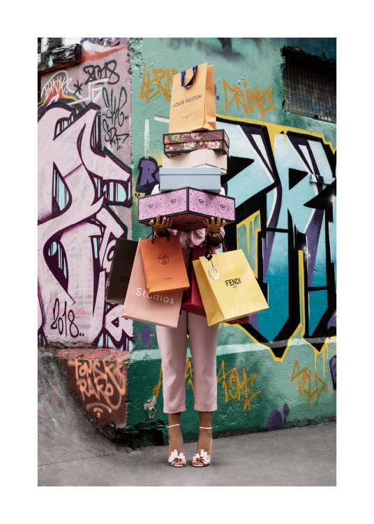  – Photographie d’une femme portant des sacs de courses et des boîtes de chaussures devant un mur de graffitis