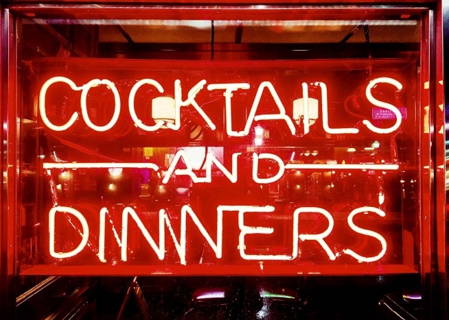 –Enseigne lumineuse rouge vif avec un restaurant en arrière–plan.