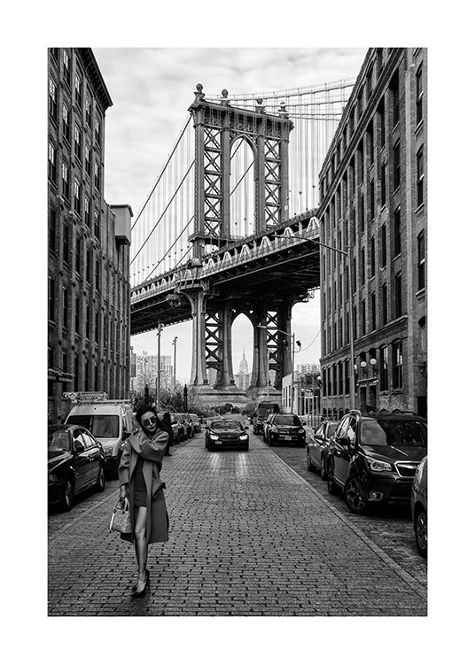  – Photographie en noir et blanc d’une femme dans une rue de New York devant le pont de Manhattan