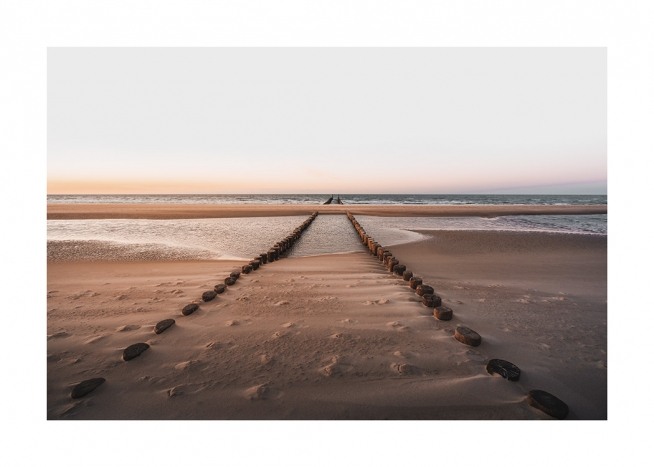  – Photographie de pieux en bois dans le sable sur une plage menant à l’océan