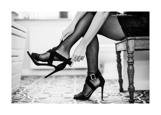  – Photographie en noir et blanc d’une femme enfilant une paire de talons