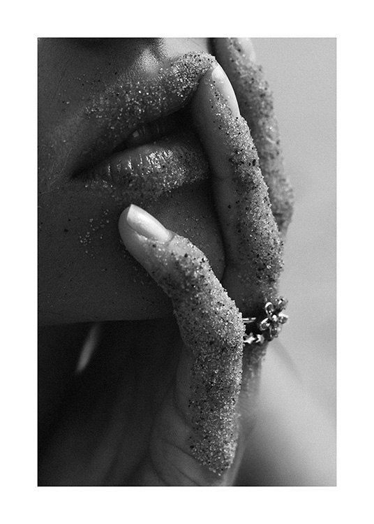  – Photographie en noir et blanc d’un gros plan d’une femme avec les lèvres et les doigts pleins de sable