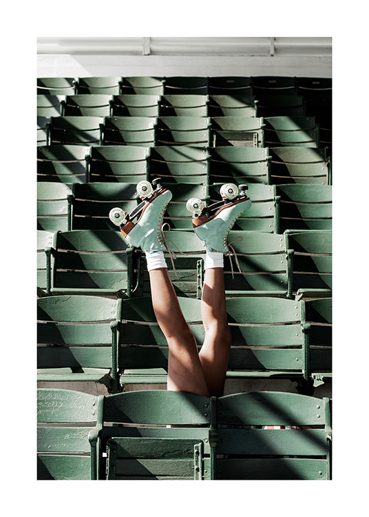  – Photographie d'une personne portant des patins à roulettes étirant ses jambes vers le haut au milieu des sièges verts d'un stade