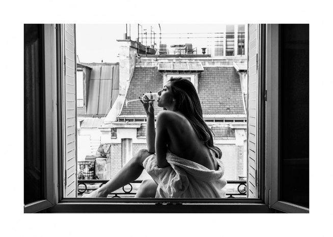  – Photo en noir et blanc d’une femme assise devant une fenêtre et buvant un verre de vin