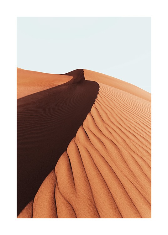  – Photographie d’une dune de sable dans un désert avec un ciel bleu clair derrière
