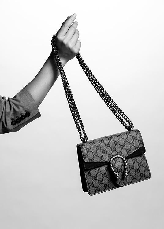  – Photo en noir et blanc d’un sac à main Gucci tenu par une main de femme