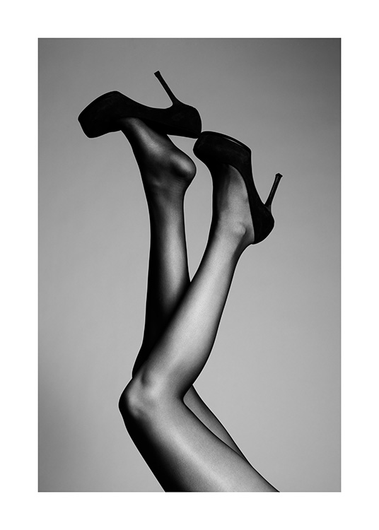  – Photographie en noir et blanc de deux jambes tendues en l’air, avec des talons hauts noirs