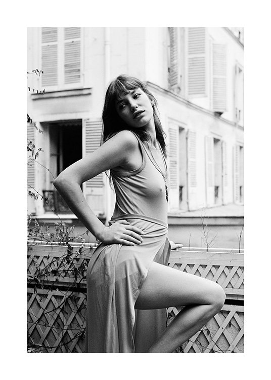  – Photographie en noir et blanc de Jane Birkin avec sa main sur la hanche, debout sur un balcon