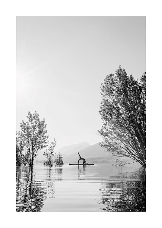  – Photo en noir et blanc d’une femme dans une pose de yoga sur une planche de surf au milieu d’un lac