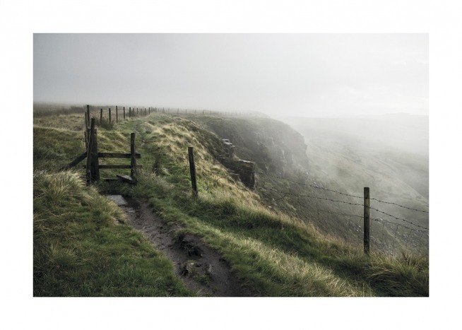  – Photographie d’un paysage verdoyant couvert de brouillard, avec un chemin le long d’une clôture au sommet de la colline