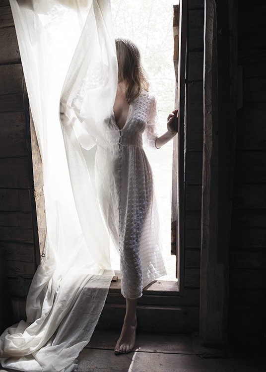  – Photographie d’une femme se tenant dans l’embrasure d’une porte et portant une robe blanche, couverte d’un rideau blanc