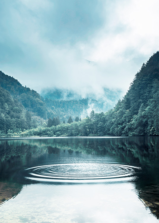  – Photographie de ronds sur l’eau dans un lac, avec une grande forêt et du brouillard à l’arrière-plan