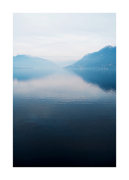  – Photographie d’un lac à la surface immobile, avec des montagnes et du brouillard à l’arrière-plan