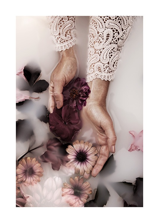  – Photographie de fleurs violettes et roses dans un bain de lait, tenues par deux mains