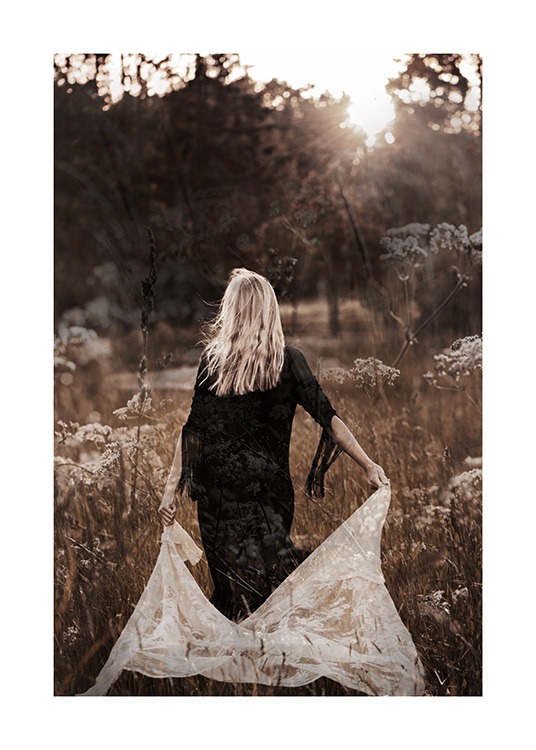  – Photographie d’une femme marchant dans un champ en robe noire, tenant de la dentelle blanche derrière elle