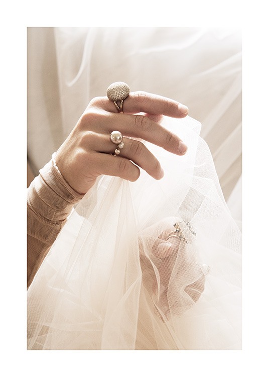  – Photographie d’une femme avec des bagues aux doigts, tenant du tulle blanc dans ses mains