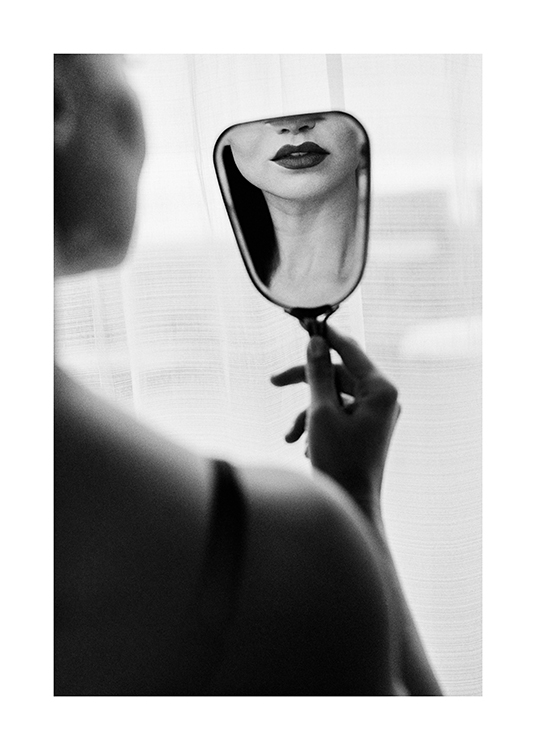  – Photographie en noir et blanc d’une femme avec un rouge à lèvres foncé se regardant dans un petit miroir
