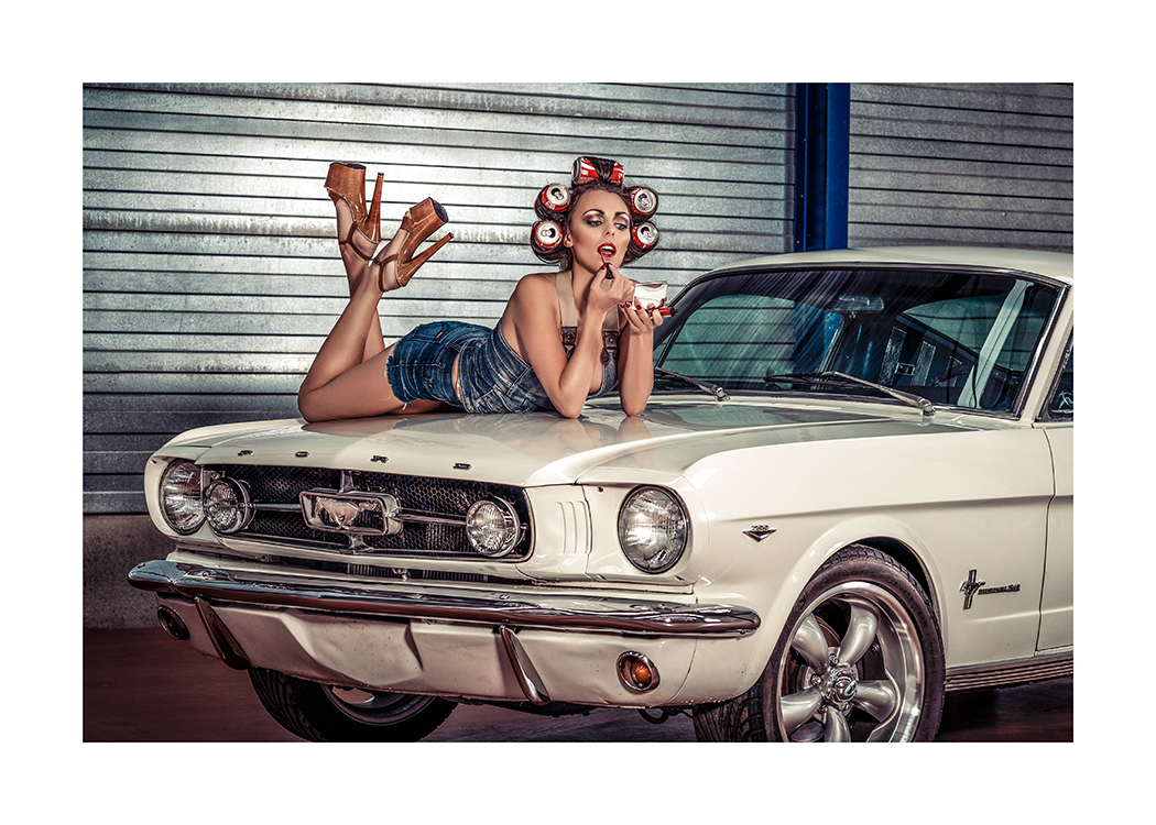  – Photographie d’une femme avec des canettes de soda dans les cheveux, allongée sur le capot d’une voiture et appliquant du rouge à lèvres