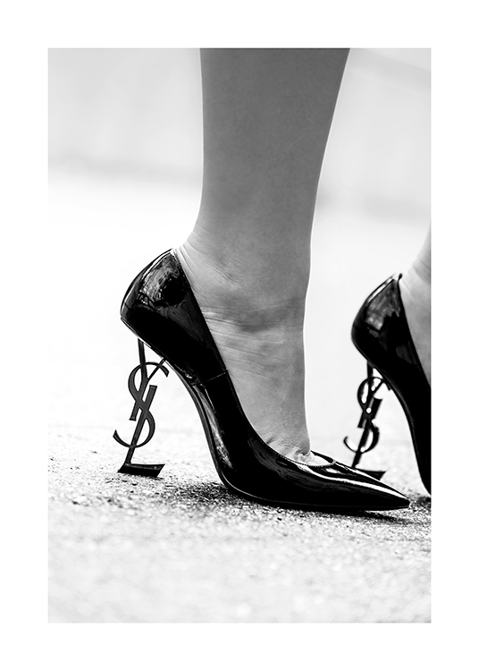  – Photographie en noir et blanc d’une paire de talons avec le logo YSL en guise de talon