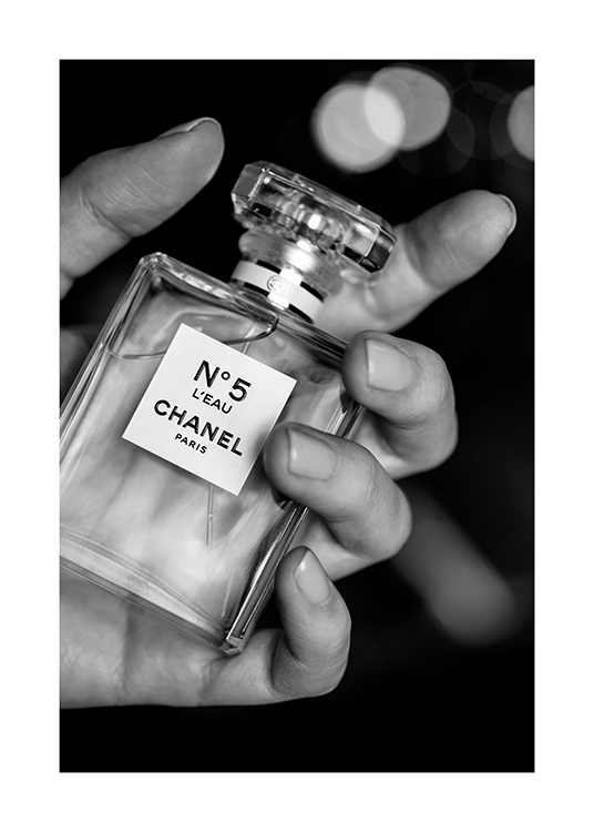 – Photographie en noir et blanc d’un flacon de parfum Chanel No5 tenu par une main