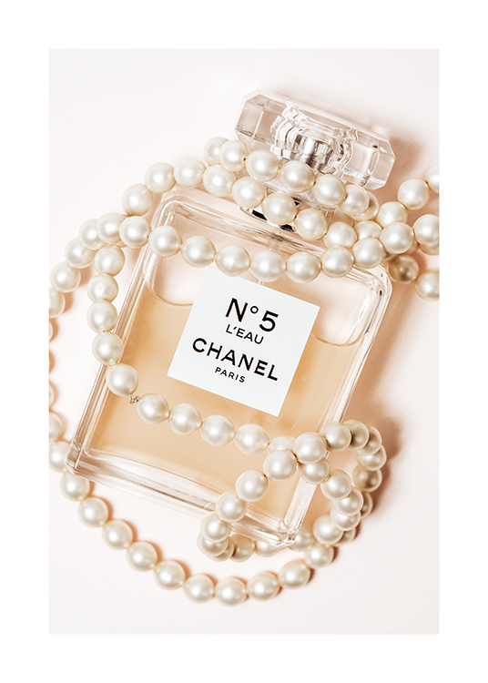  – Photographie d’un flacon de parfum avec Chanel No5 écrit dessus, enveloppé dans un collier de perles blanches