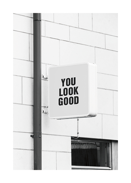  – Photographie en noir et blanc d’une enseigne de magasin sur laquelle on peut lire « You look good »