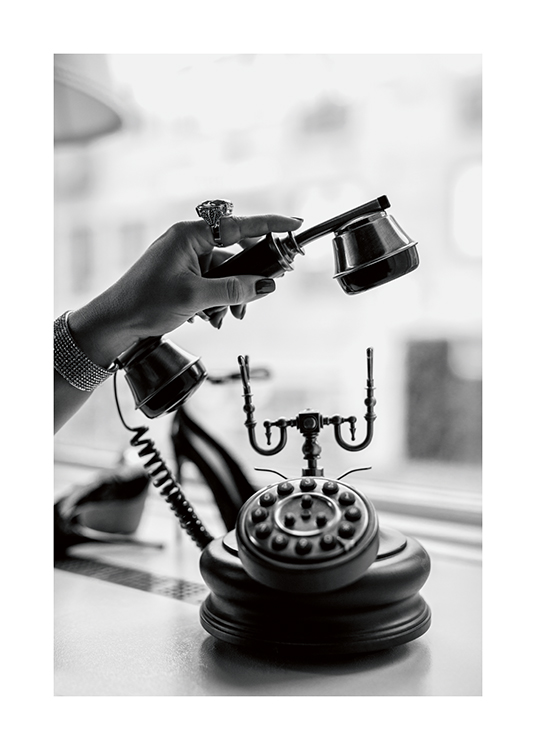  – Photo en noir et blanc d’une femme portant une énorme bague, décrochant un téléphone ancien