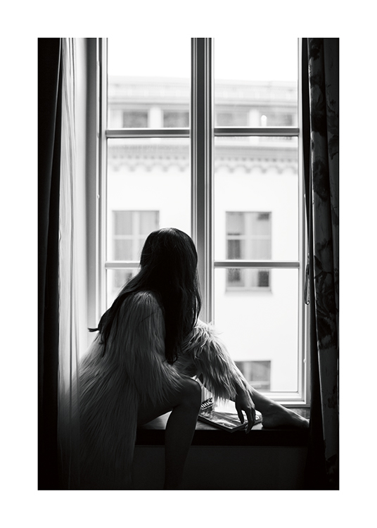  – Photo en noir et blanc d’une femme brune assise sur un rebord de fenêtre dans un manteau en fausse fourrure