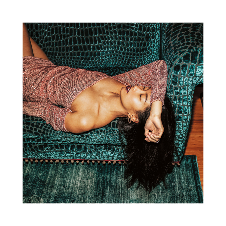  – Photographie d’une femme dans une robe scintillante faisant la sieste sur un sofa turquoise