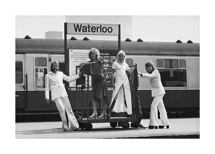  – Photographie en noir et blanc des membres du groupe ABBA devant la gare de Waterloo