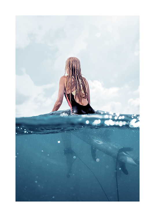  – Photographie d’une femme assise sur une planche de surf dans l’océan, vue de dos