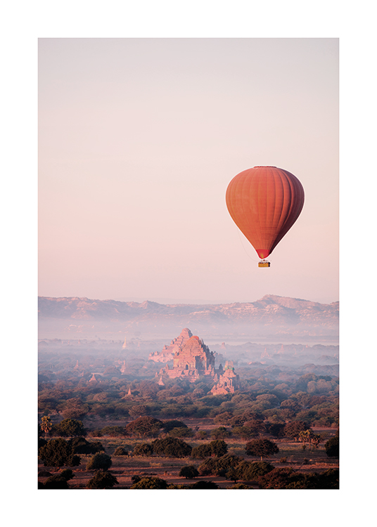  – Photographie d’une montgolfière rouge dans les airs avec un paysage de montagne et de forêt à l’arrière-plan