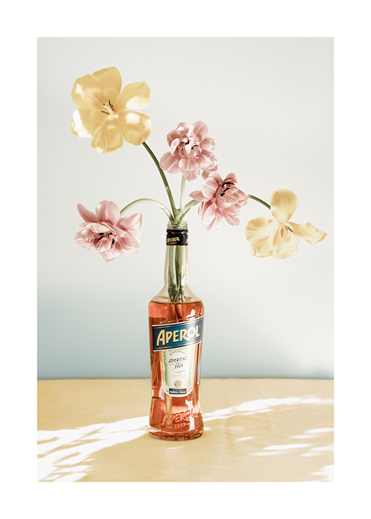  – Photographie de fleurs en rose et jaune dans une bouteille d’Aperol