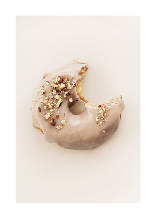  – Photographie d’un donut avec glaçage beige et éclats de noisettes