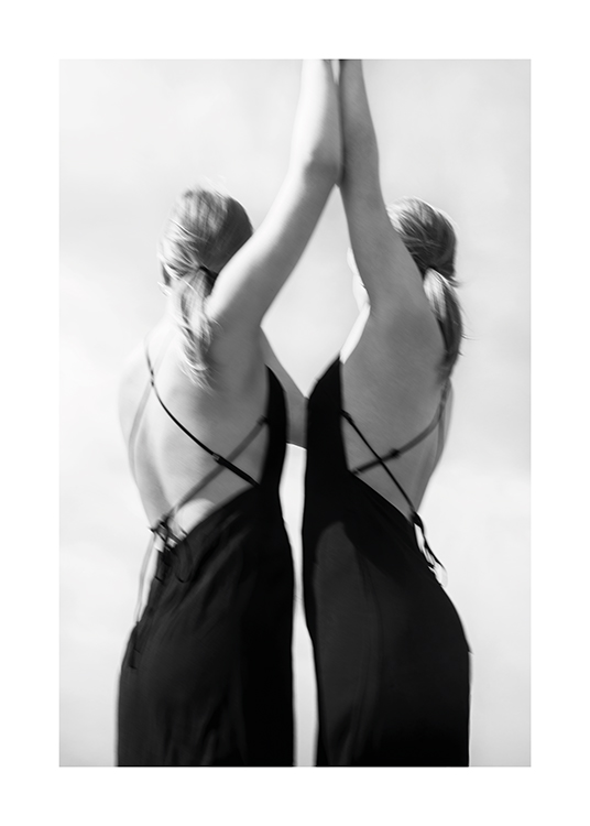  – Photographie en noir et blanc d’un couple de femmes joignant leurs mains vers le haut