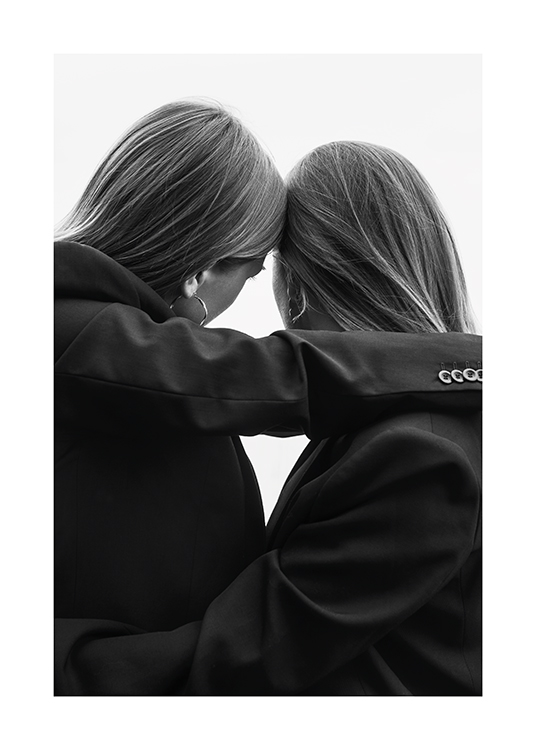  – Photographie en noir et blanc de deux femmes en tailleur appuyant leur tête l’une contre l’autre