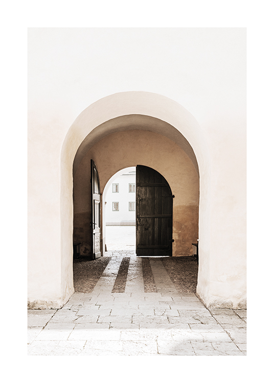  – Photographie d’une porte cintrée en bois sombre vue à travers une arche dans un bâtiment clair