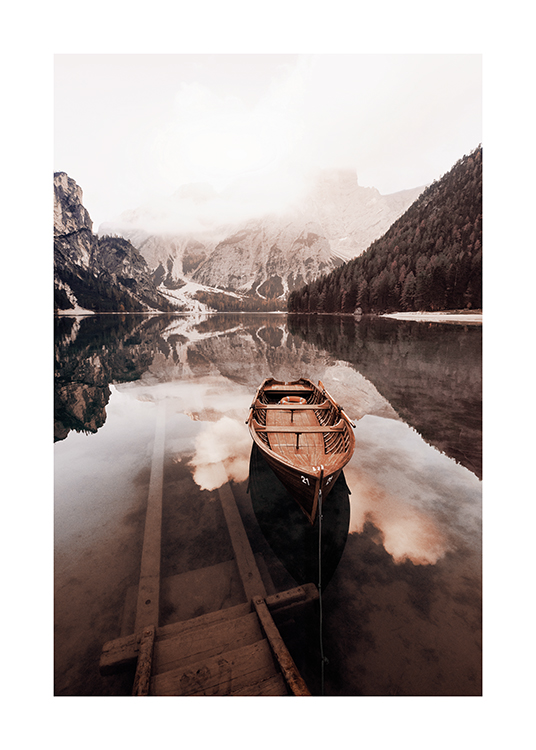  – Photographie d’un lac immobile avec une barque en bois et des montagnes enneigées à l’arrière-plan