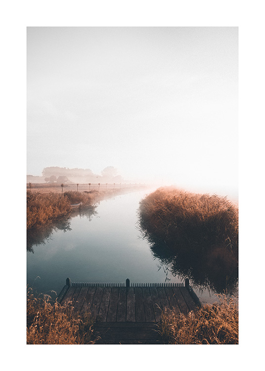 – Photographie d’un lac calme avec un paysage brumeux à l’arrière-plan et une petite jetée au premier plan