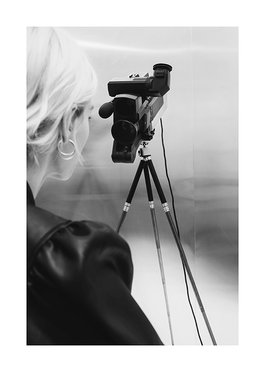 – Photographie en noir et blanc d’une femme aux cheveux blonds derrière une caméra